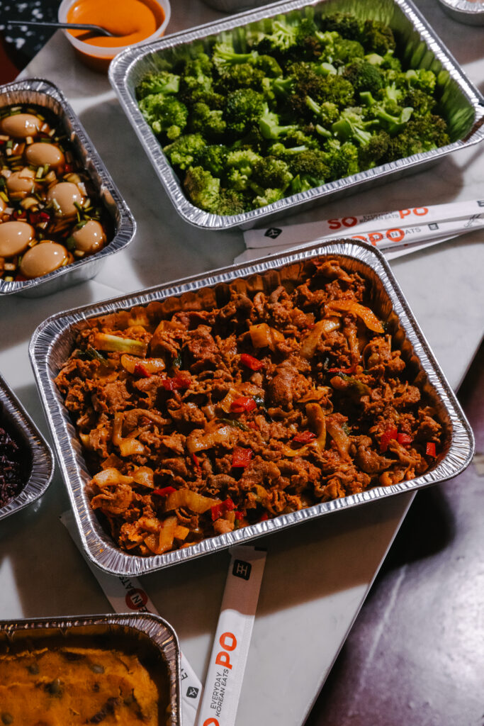 Korean catering platters of bulgogi, spicy pork, sides, and kimbap for an NYC office team lunch